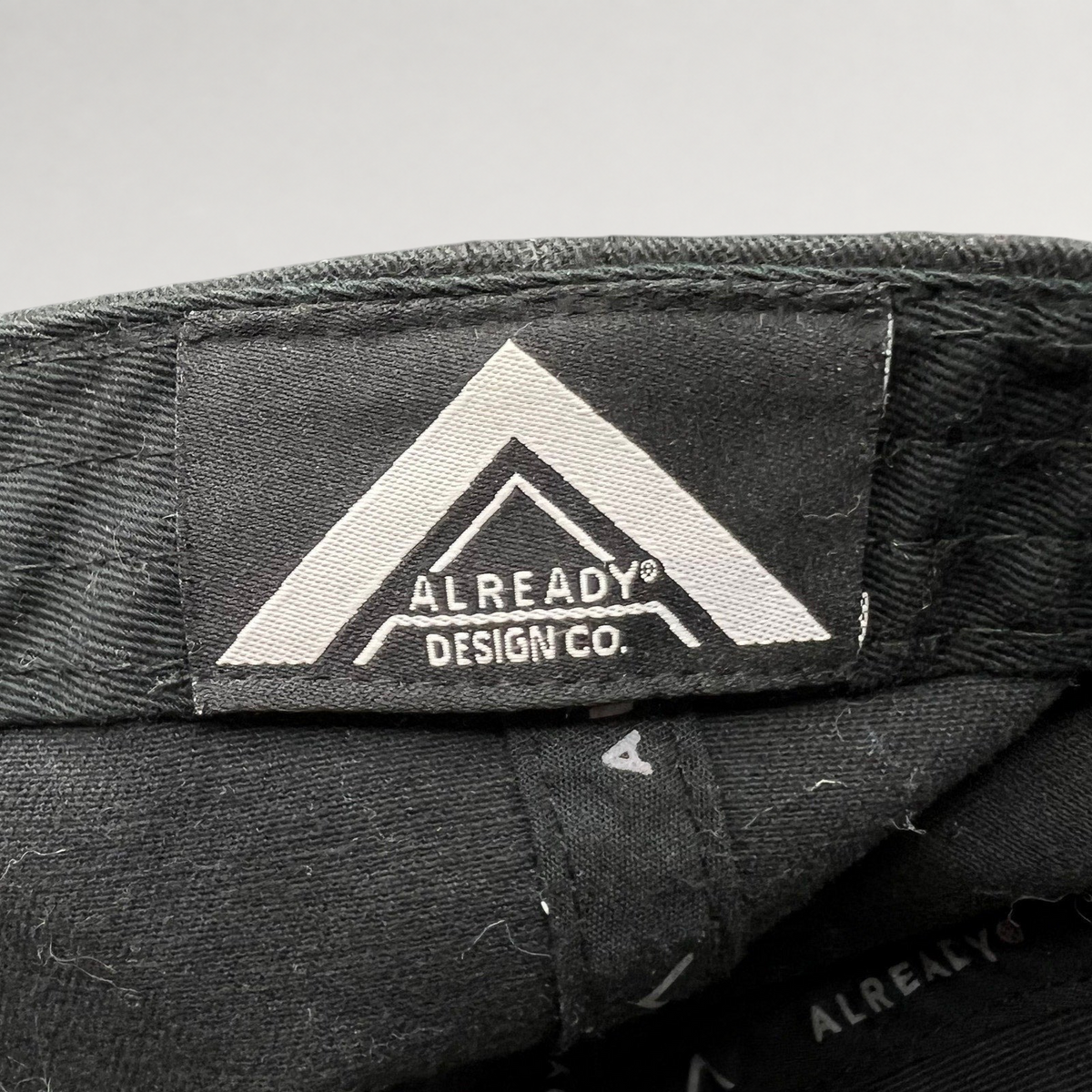 Raree Finds black strapback hat interior label featuring the Already Design Co. logo on a cotton blend fabric.