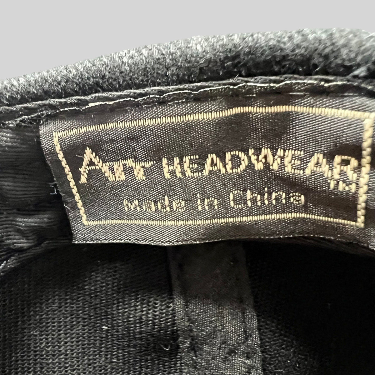 Raree Finds black cap interior label showing Art Headwear branding and made in China text on a fabric tag.