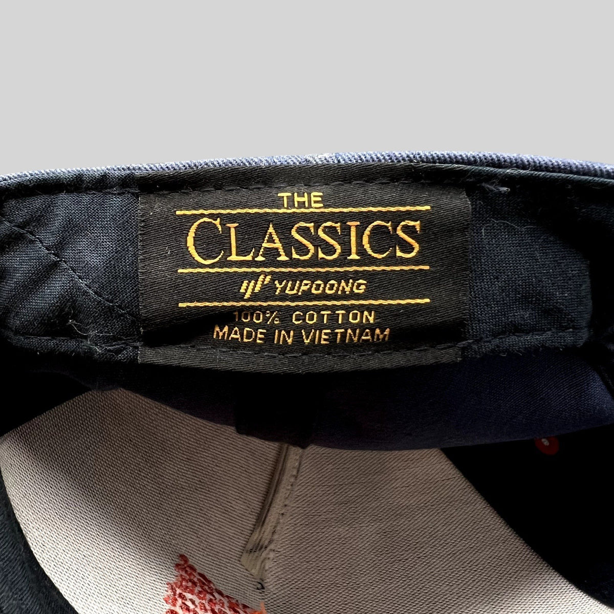 Raree Finds Atomic Skis snapback interior label showing Yupoong The Classics branding and 100% cotton material tag