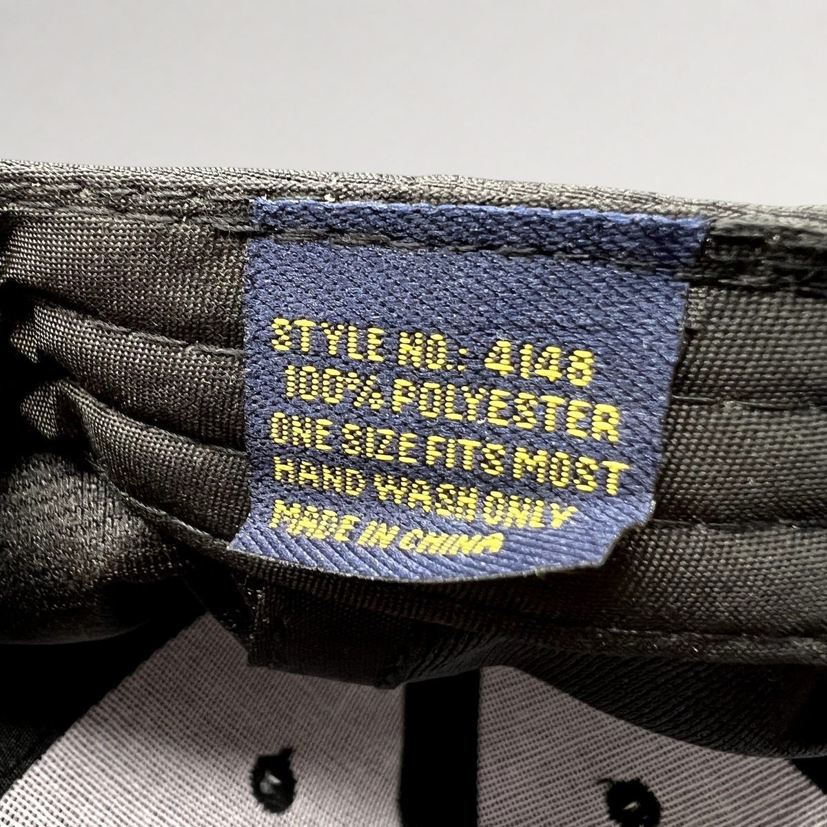 Raree Finds black hat interior tag showing 100 percent polyester material and care instructions