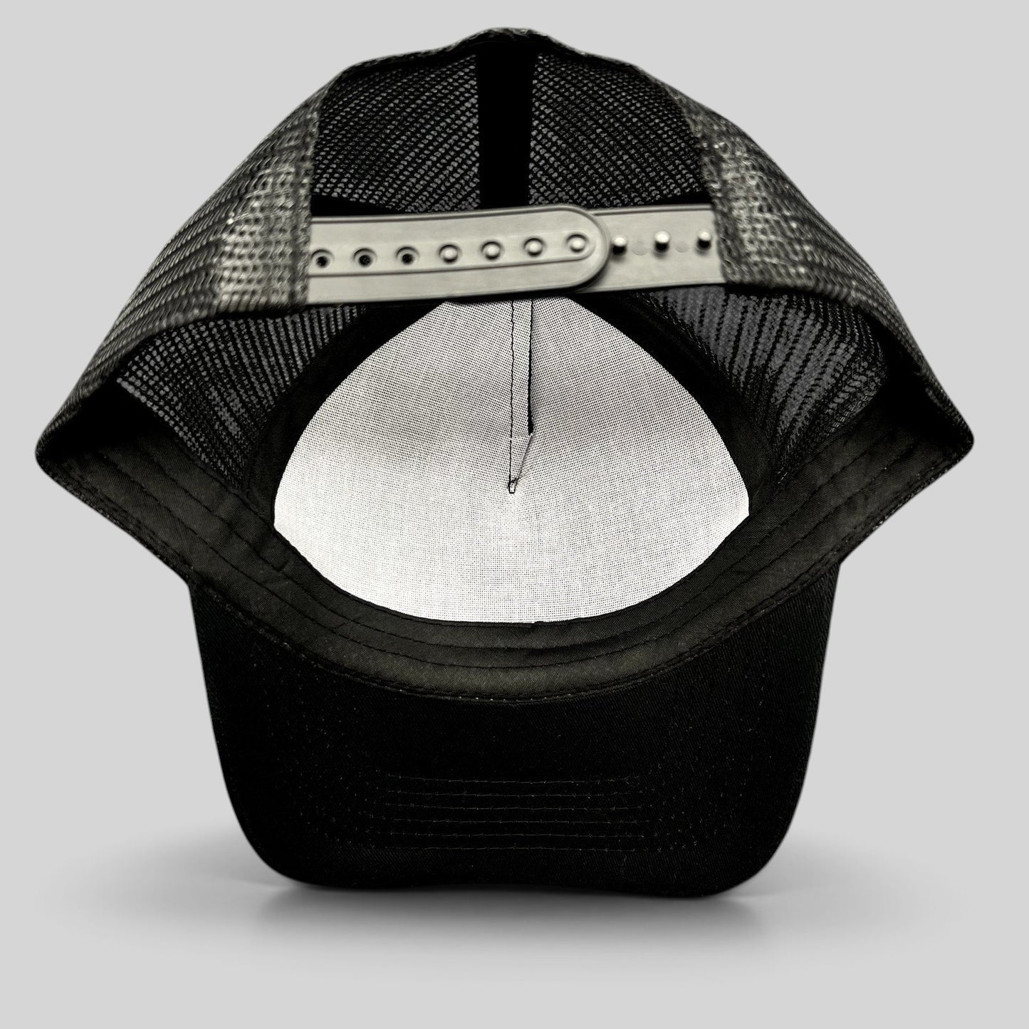 Raree Finds black mesh trucker hat showing the adjustable snapback closure and interior crown view