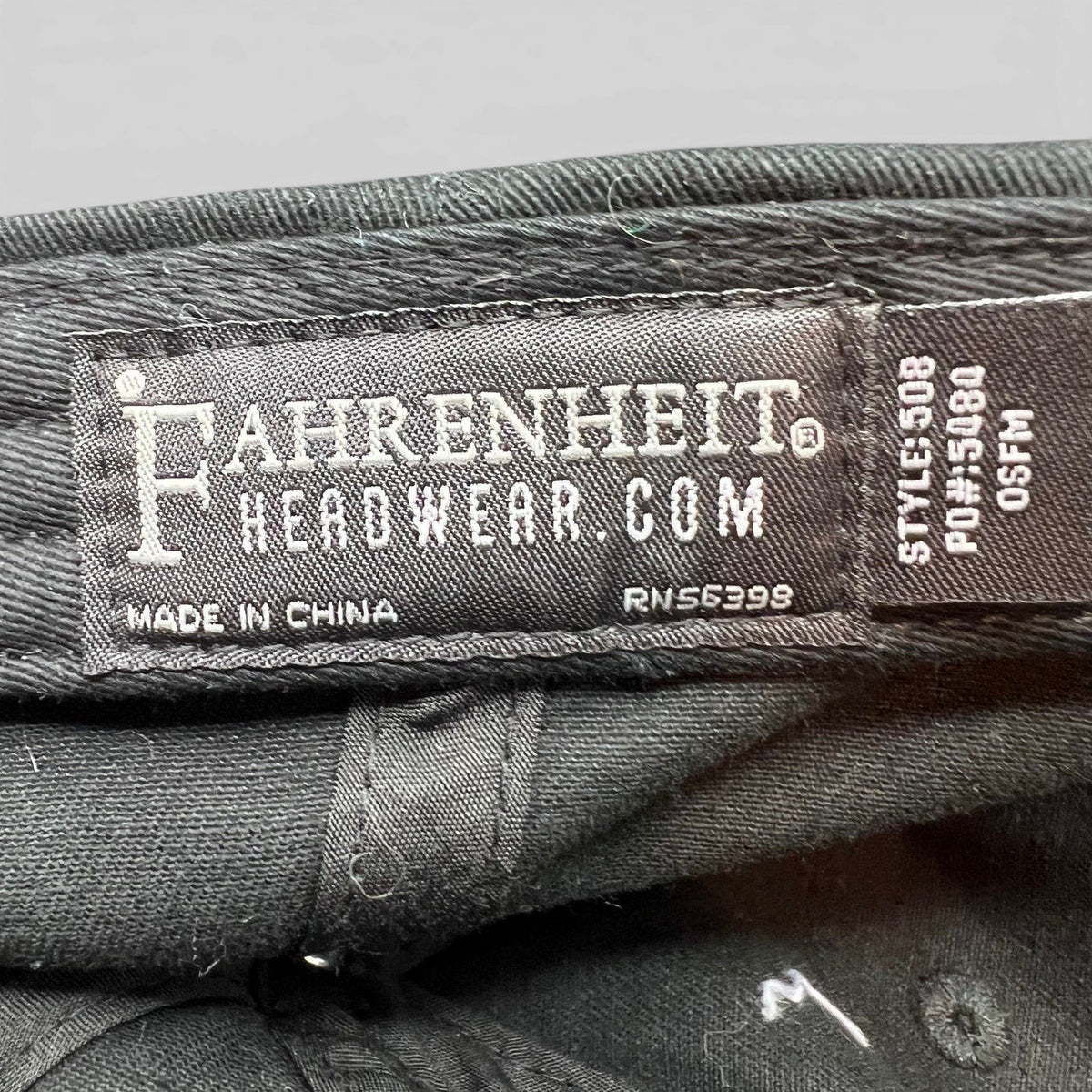Raree Finds black cotton strapback hat interior label showing Fahrenheit Headwear branding and manufacturing details