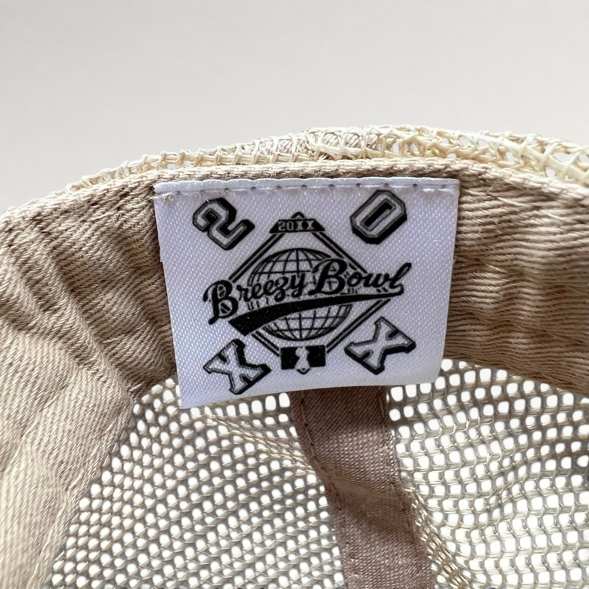 Raree Finds Breezy Bowl XX trucker hat interior label with globe logo and 20th anniversary branding on mesh fabric