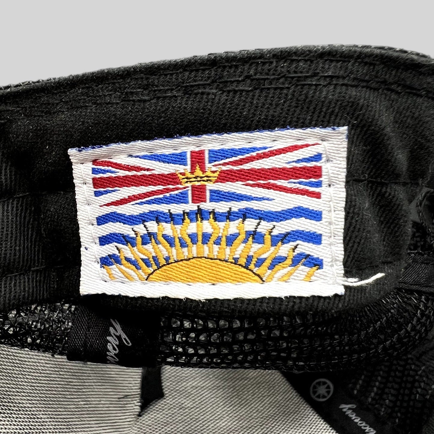 Raree Finds Discovery Collection trucker hat interior tag featuring a detailed embroidered British Columbia flag patch.
