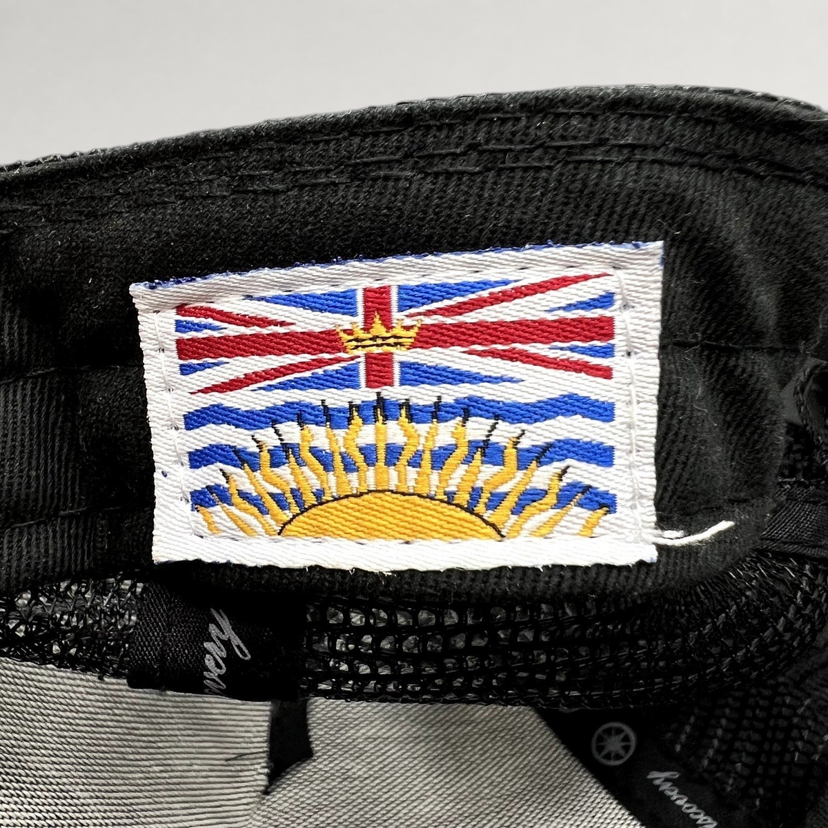 Raree Finds Discovery Collection trucker hat interior tag featuring a detailed embroidered British Columbia flag patch.