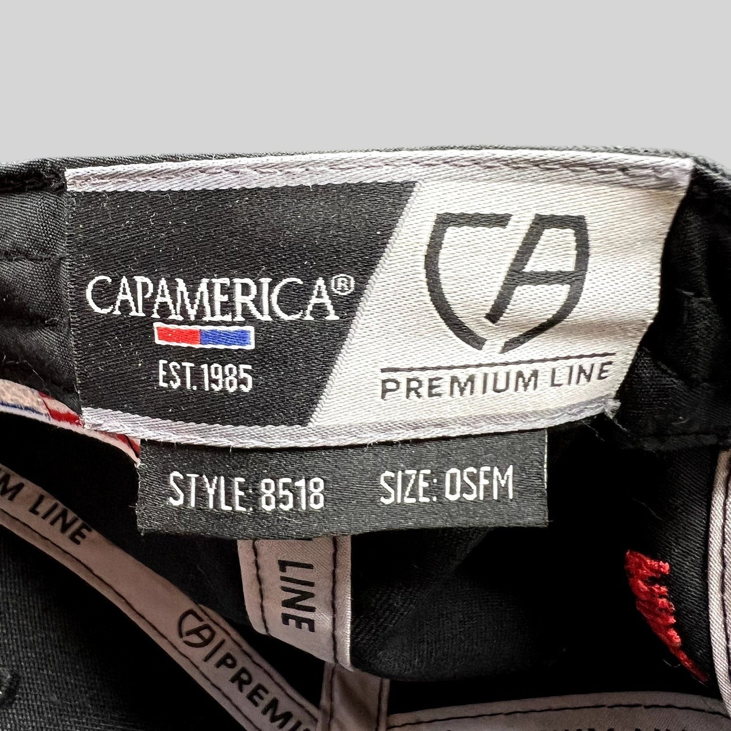 Raree Finds Cap America Premium Line interior tag showing style 8518 and OSFM size on a black racing snapback hat