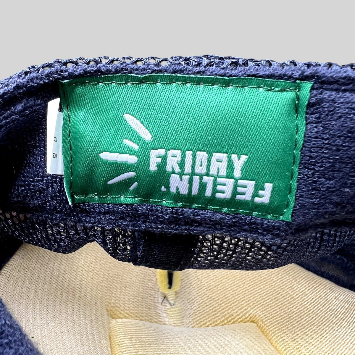 Raree Finds Friday Feelin’ green interior brand label inside a navy blue mesh trucker hat