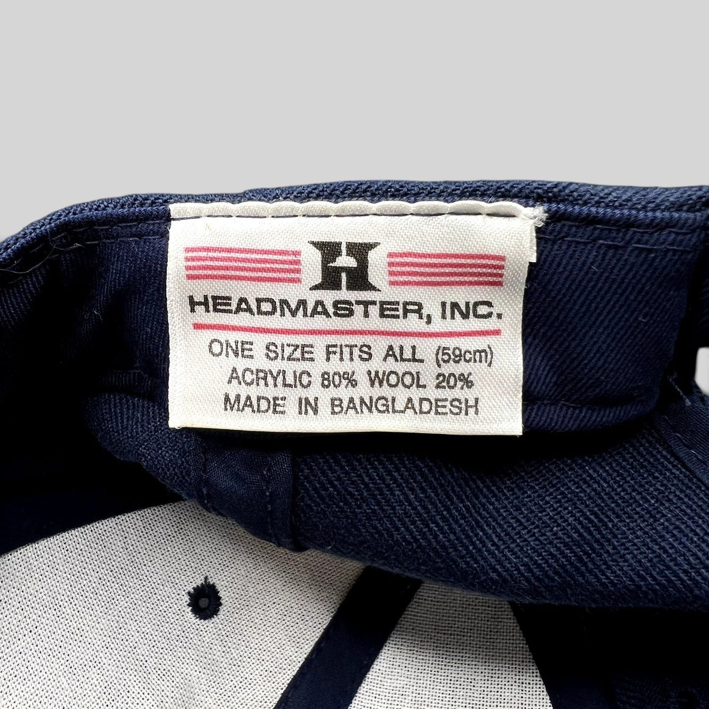 Raree Finds Headmaster hat interior tag showing brand logo, material composition, and origin on navy blue fabric
