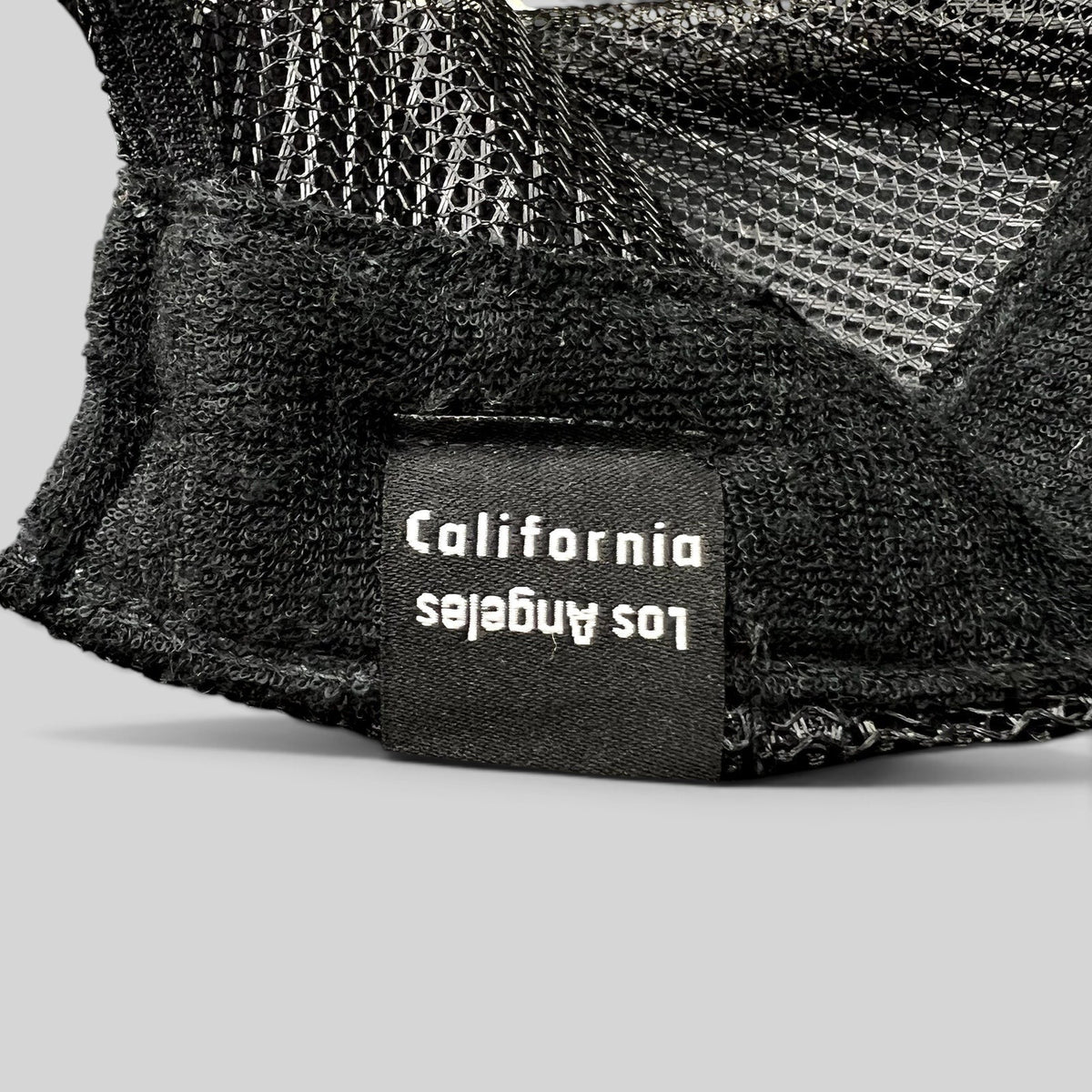 Raree Finds black trucker hat interior tag featuring Los Angeles California text on a mesh back cap