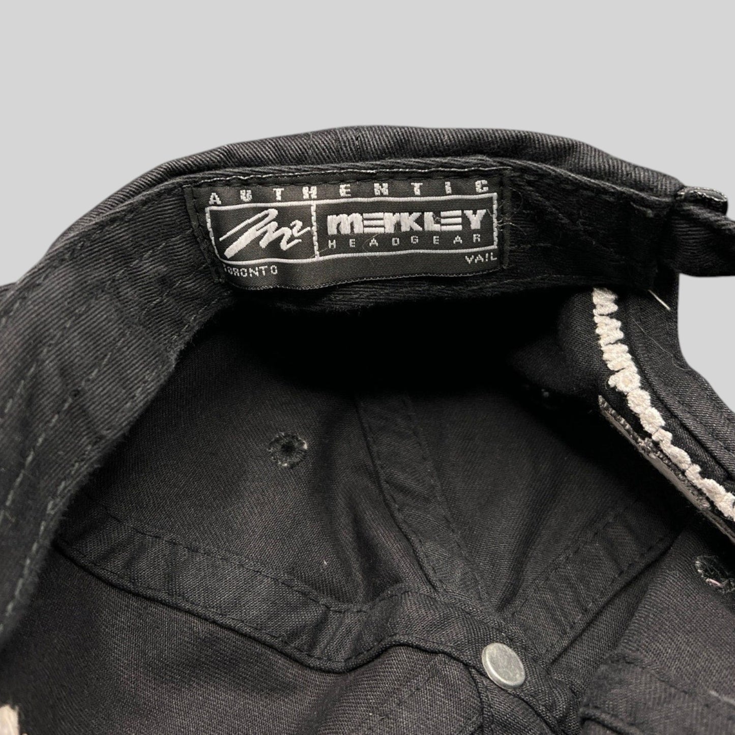 Raree Finds black cotton hat interior showing the Merkley Headgear authentic label and unstructured 6-panel stitching.