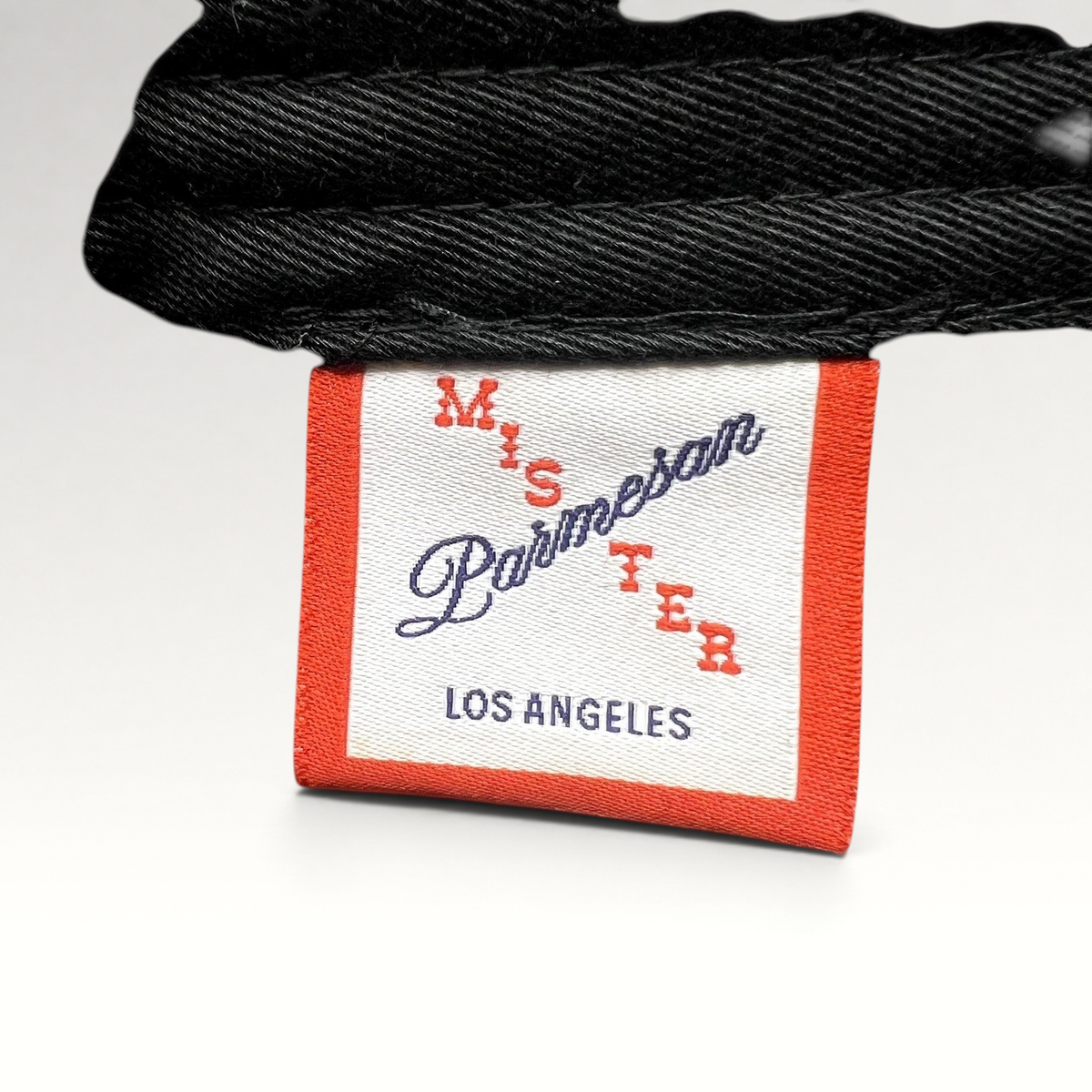 Raree Finds Mister Parmesan Los Angeles clothing brand label tag on a black cotton strapback hat