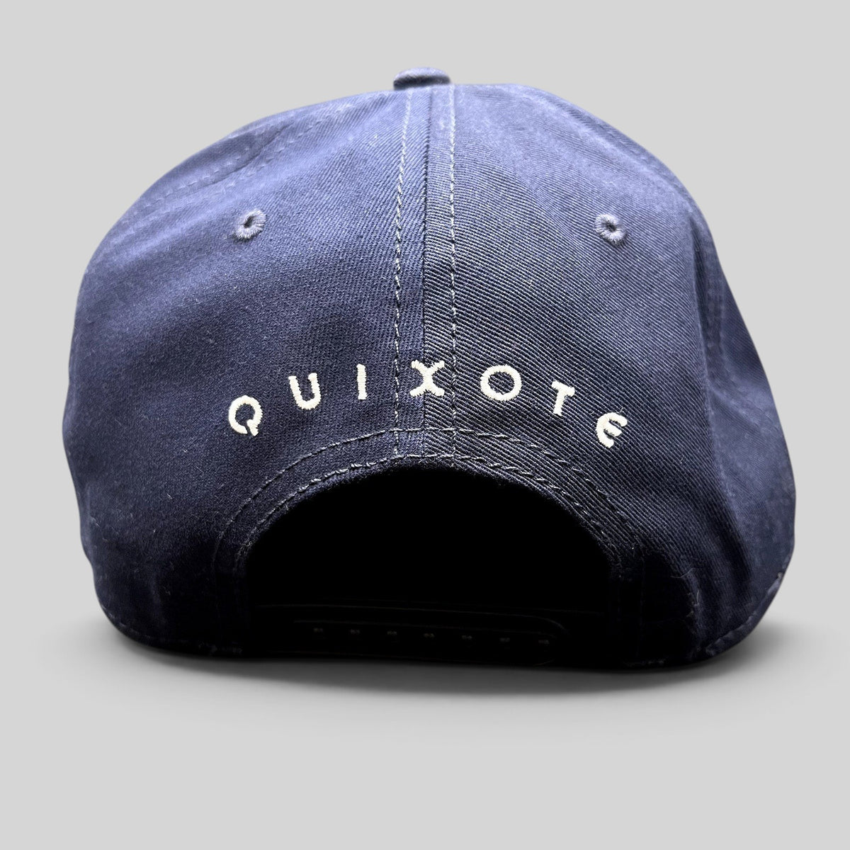 Raree Finds navy blue snapback hat featuring white Quixote embroidery on the back of the structured crown