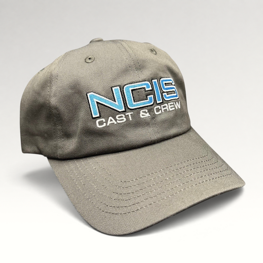 Raree Finds gray NCIS Cast & Crew strapback hat with blue and white embroidered logo on a curved bill cap.