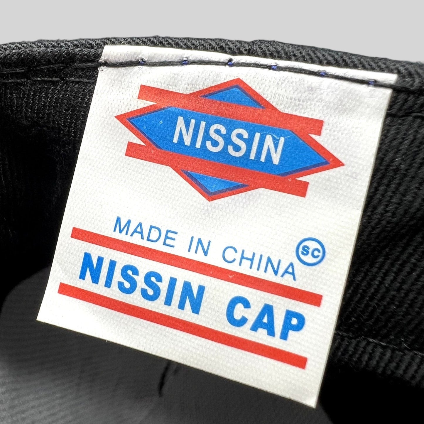 Raree Finds vintage Nissin Cap brand label on a black cotton twill strapback hat interior