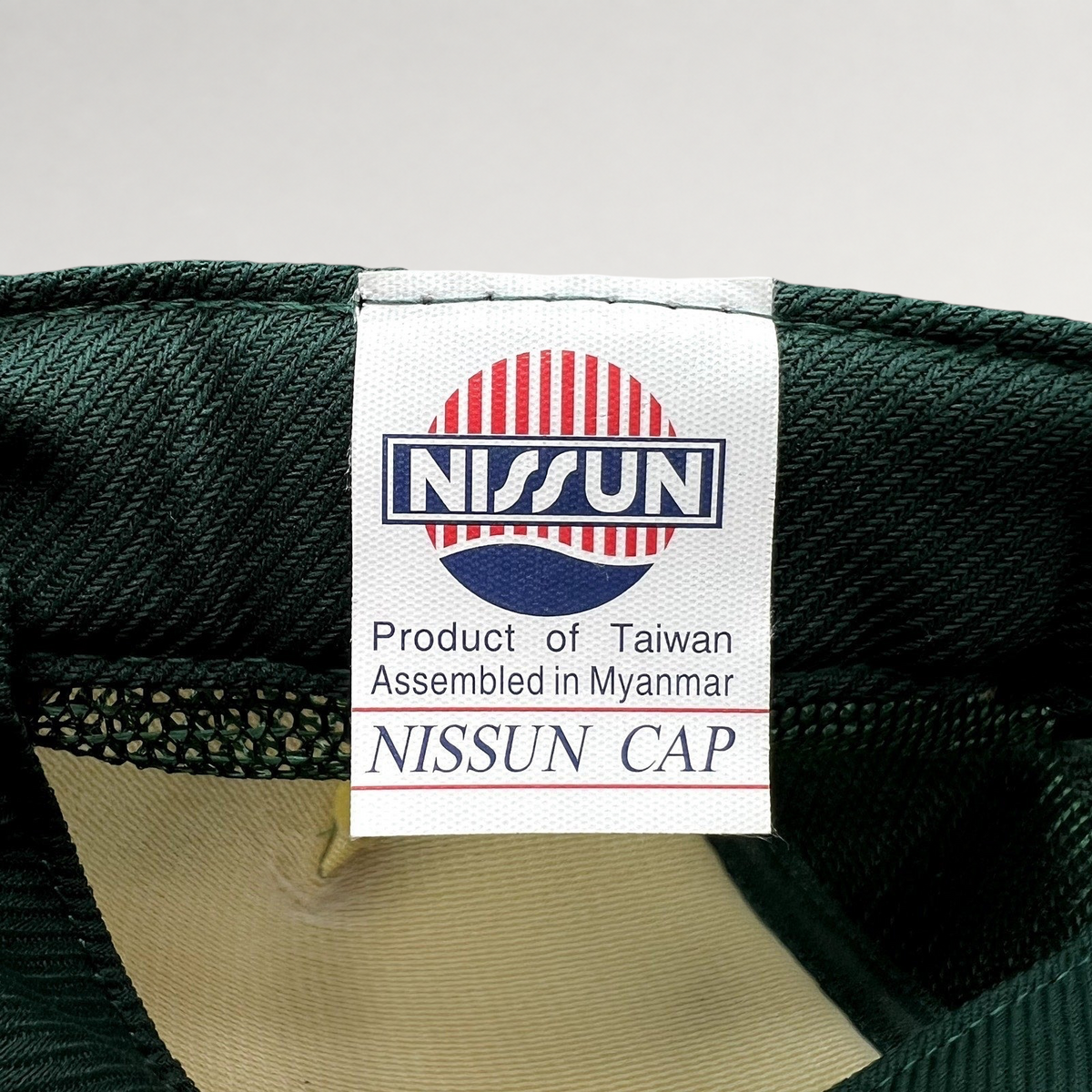 Raree Finds vintage Nissun Cap label showing manufacturing details inside a green mesh trucker hat