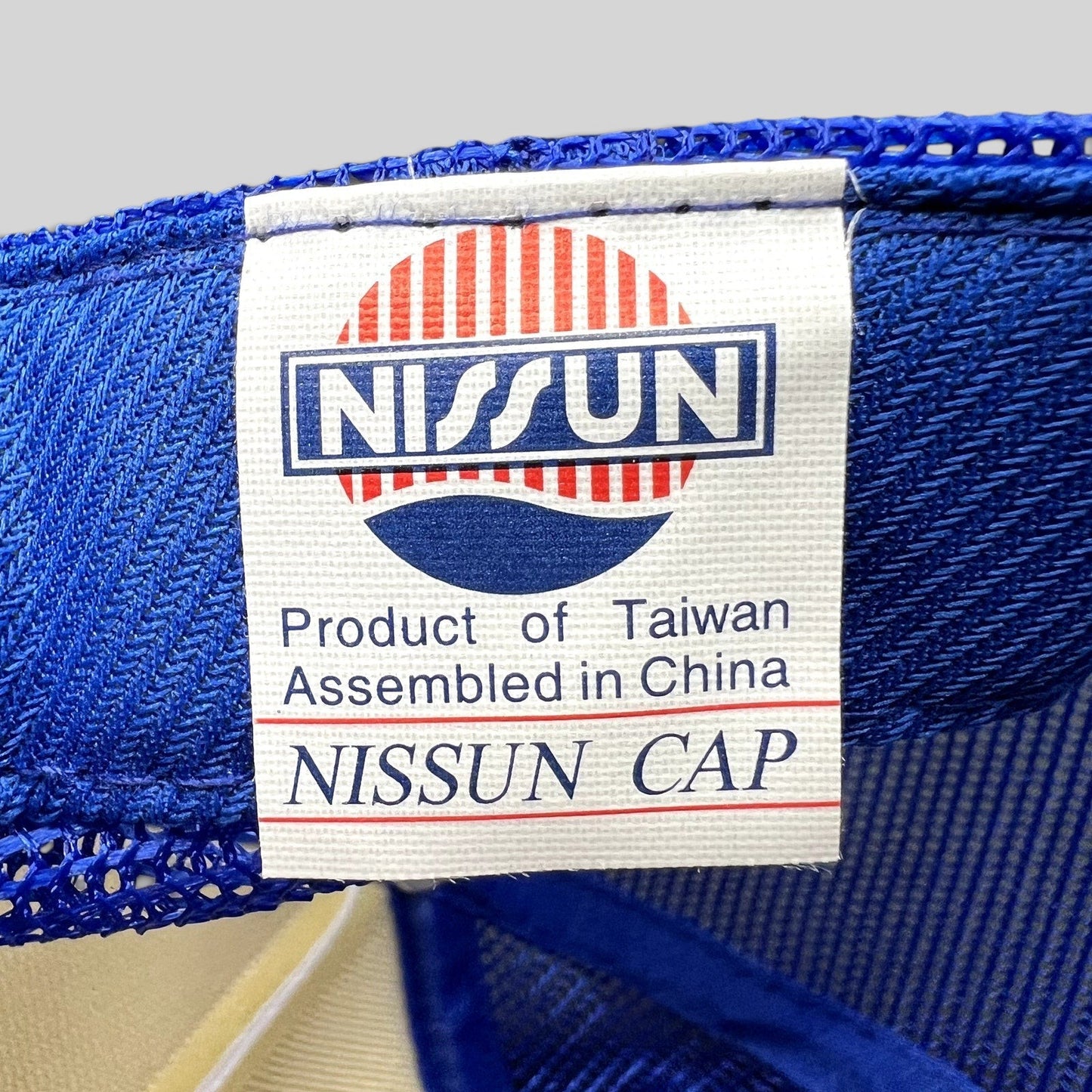 Raree Finds vintage Nissun Cap label inside a blue mesh trucker hat from 1983