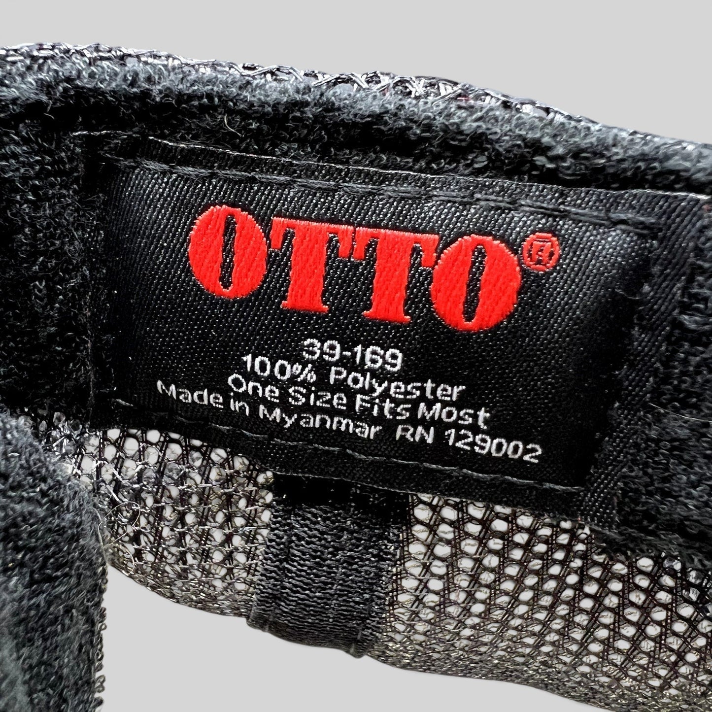 Raree Finds OTTO trucker hat interior tag showing red logo, 100 percent polyester material, and Myanmar origin
