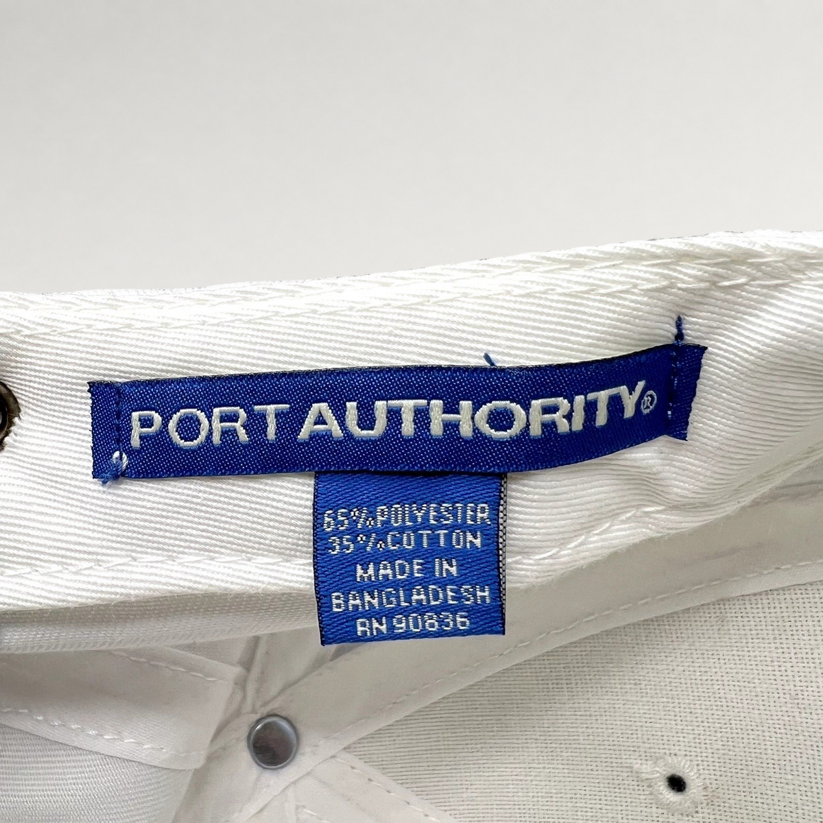 Raree Finds white Port Authority hat interior label showing 65 percent polyester and 35 percent cotton material blend