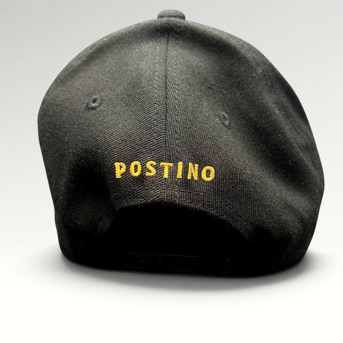Raree Finds black snapback hat with yellow POSTINO embroidery on the back, featuring a structured Yupoong 110 design.