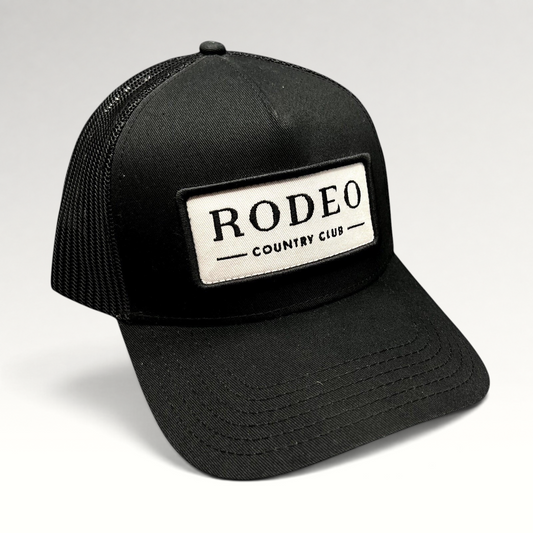 Raree Finds black Rodeo Country Club trucker hat with a white embroidered patch and breathable mesh back panel.