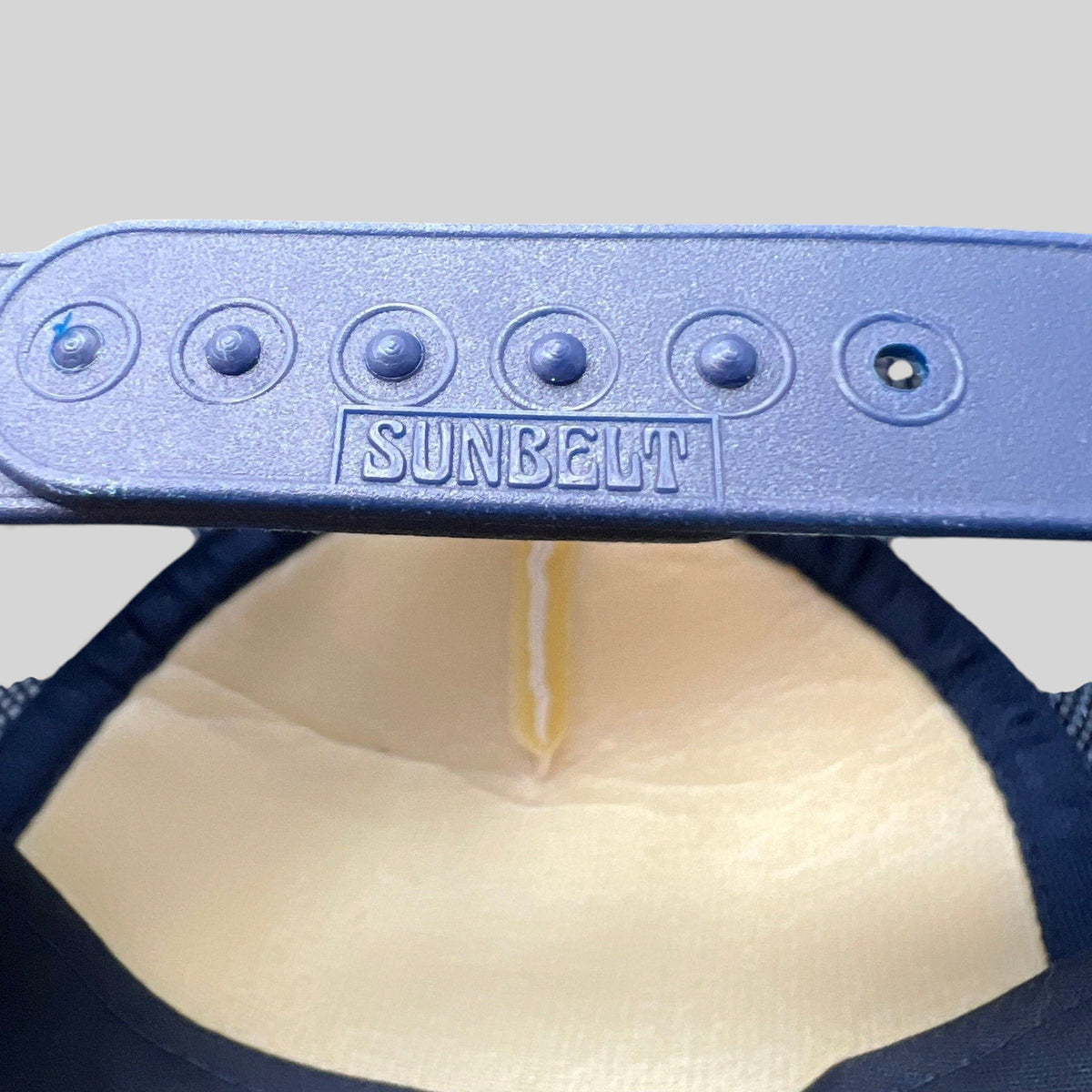 Raree Finds vintage Sunbelt snapback trucker hat showing the navy plastic adjustable strap with embossed logo