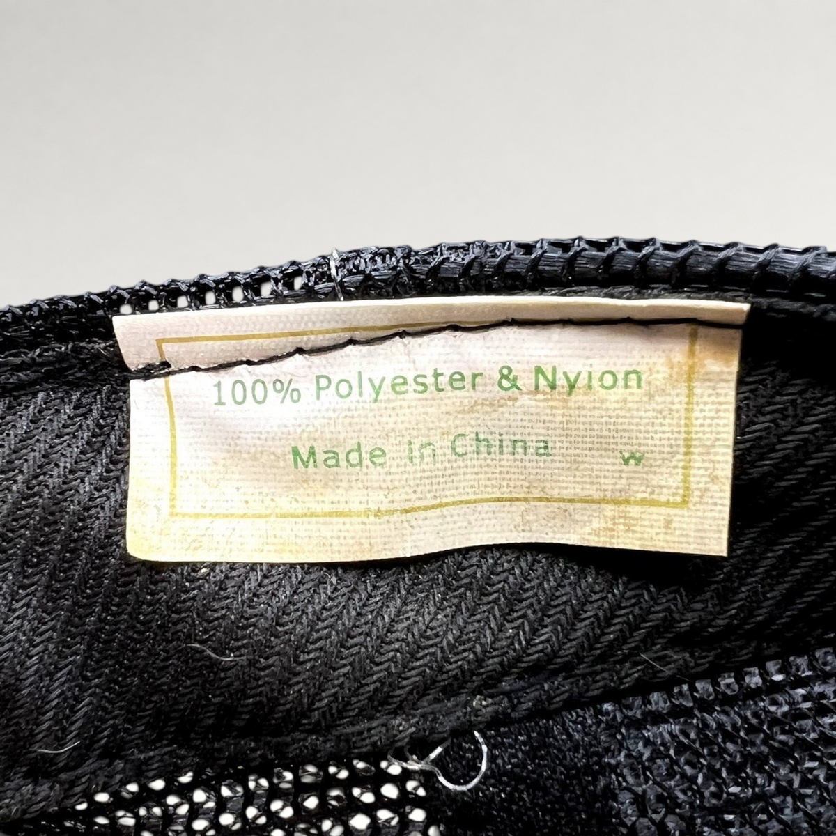 Raree Finds vintage trucker hat interior tag showing 100 percent polyester and nylon material composition