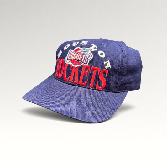 Raree Finds vintage 1990s Houston Rockets snapback hat in navy blue with red embroidered logo and green undervisor.