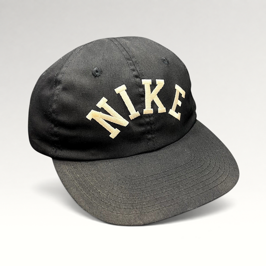 Raree Finds vintage black Nike strapback hat with an oversized arched embroidered logo and a green undervisor.