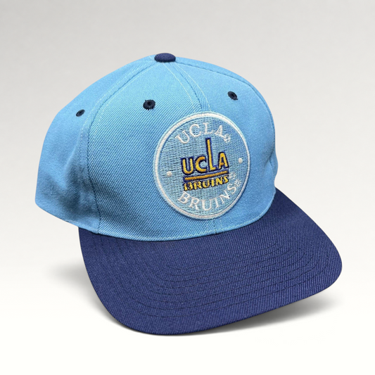 Raree Finds vintage 90s UCLA Bruins snapback hat with a light blue crown, navy brim, and circular embroidered logo.