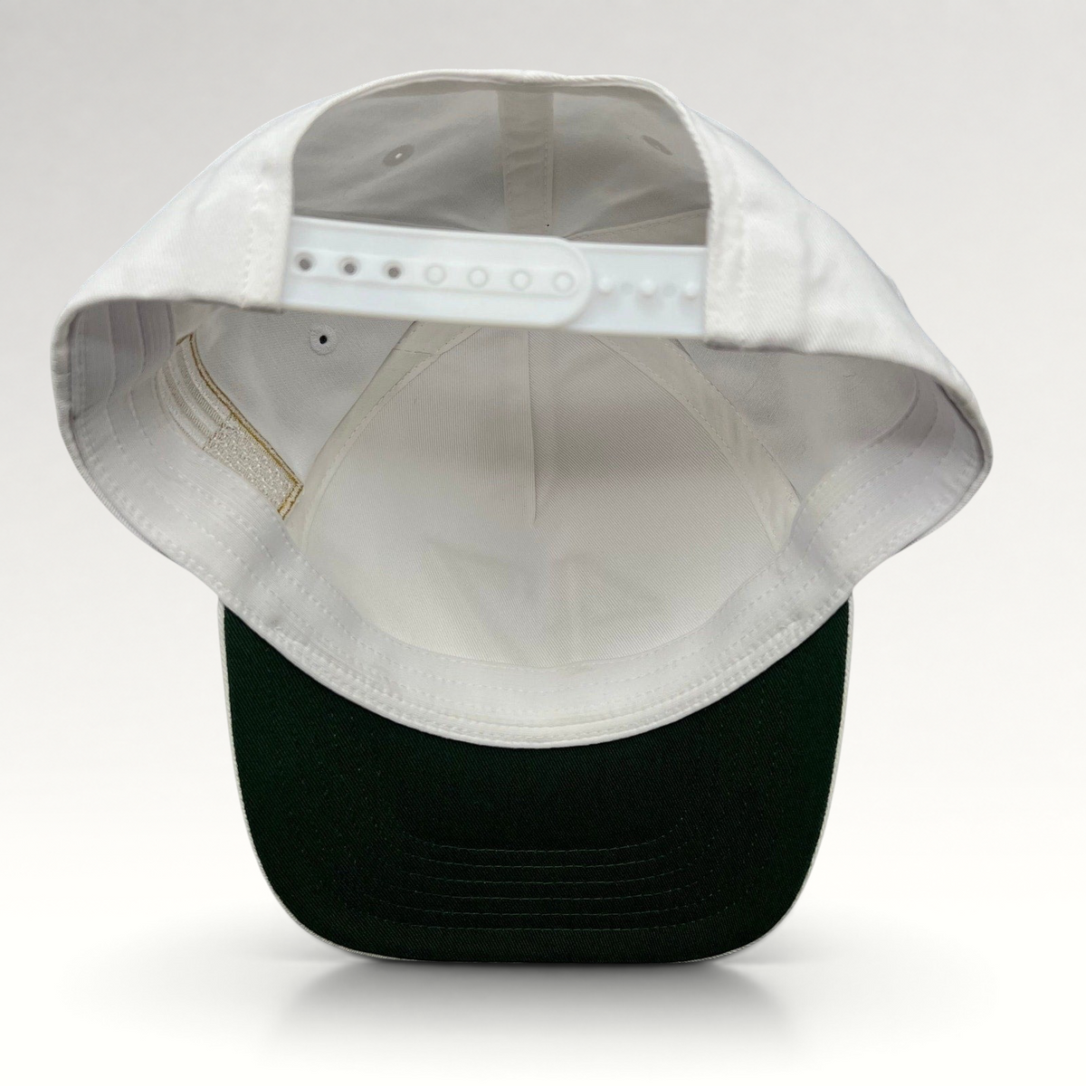 Raree Finds white cotton snapback hat with a green undervisor and adjustable plastic snap closure, back view.