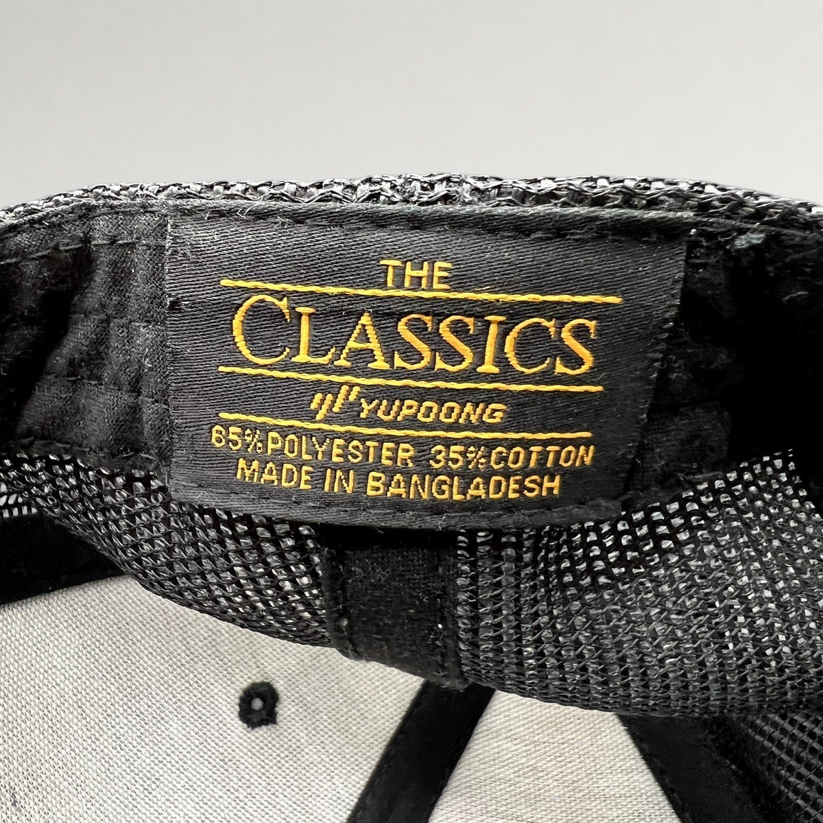Raree Finds black Yupoong Classics trucker hat interior label showing polyester cotton blend and origin details