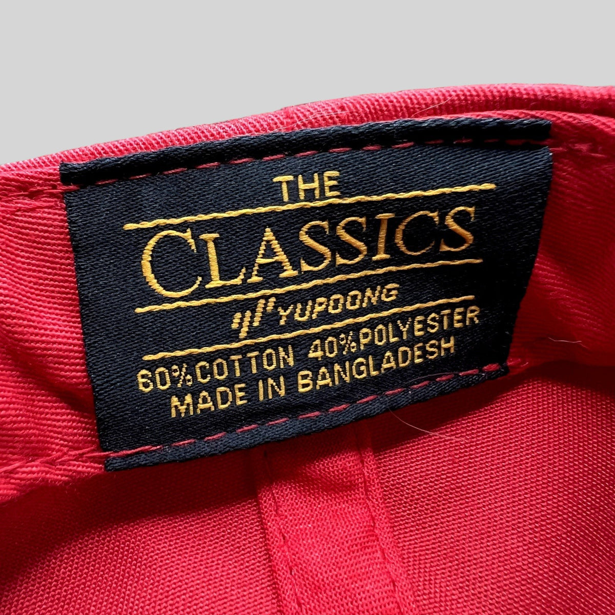 Raree Finds Yupoong The Classics interior label on a red snapback hat showing material composition and origin