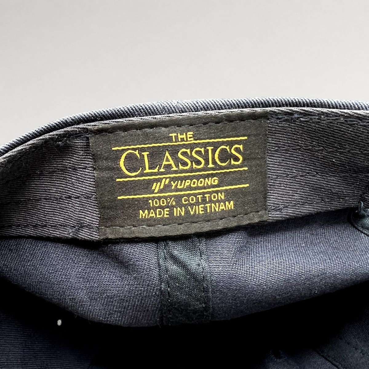 Raree Finds navy blue cotton dad cap interior featuring a Yupoong Classics brand label with gold embroidery