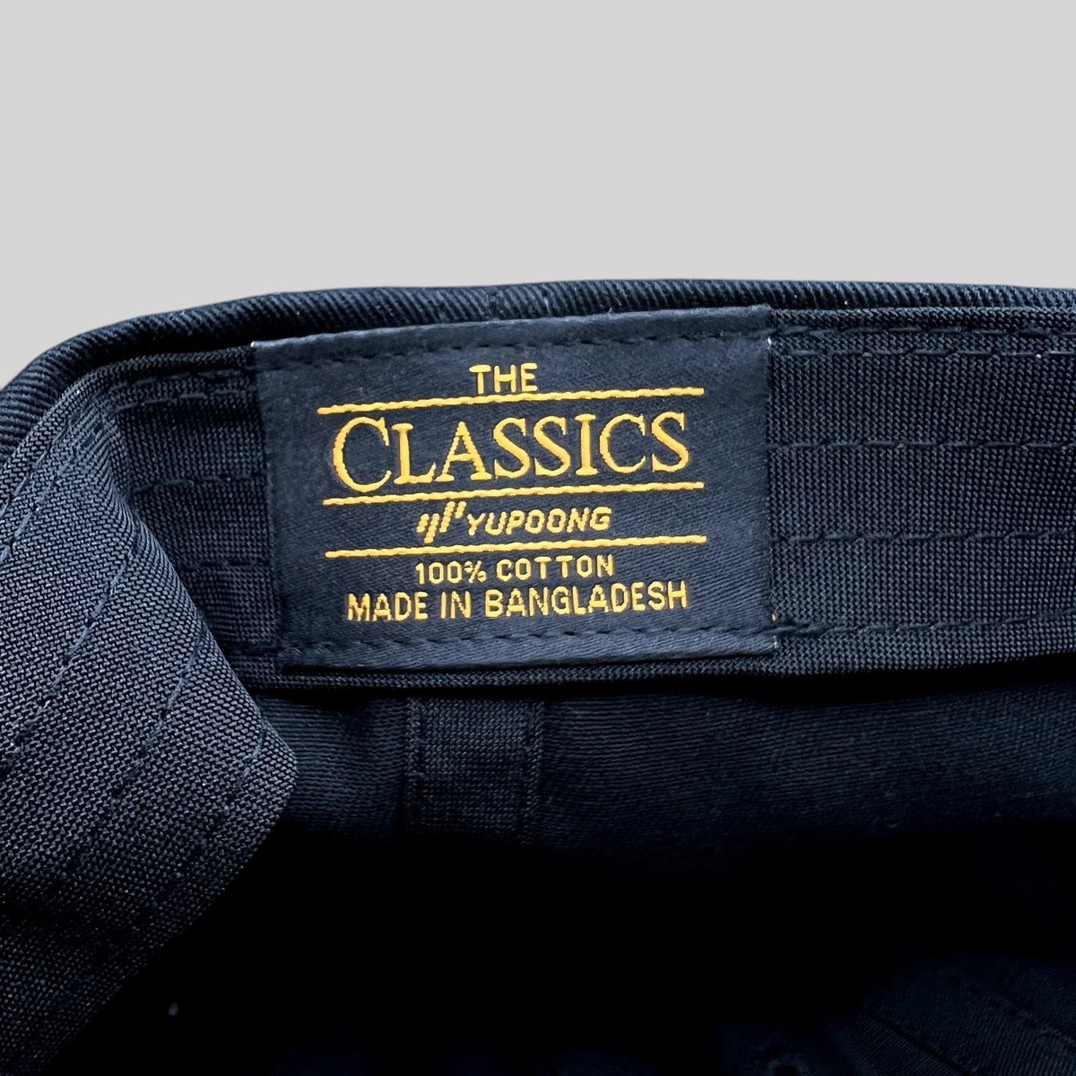 Raree Finds black cotton Yupoong Classics hat interior label with gold text detailing 100 percent cotton construction