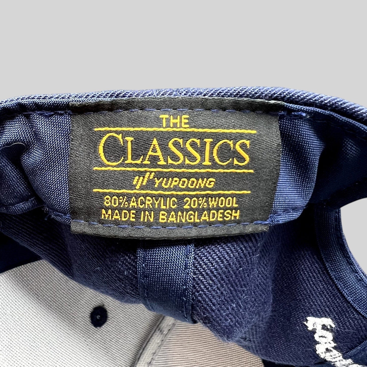 Raree Finds navy blue Yupoong Classics snapback hat interior label showing material composition and origin