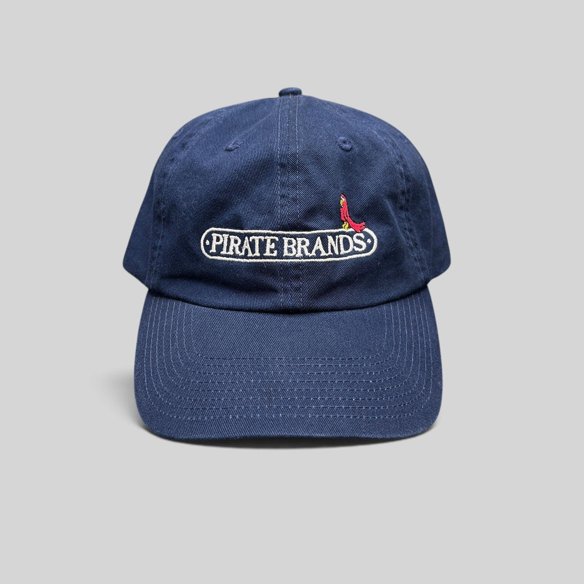 Raree Finds navy cotton dad hat with embroidered Pirate Brands logo and red parrot detail on a curved brim cap