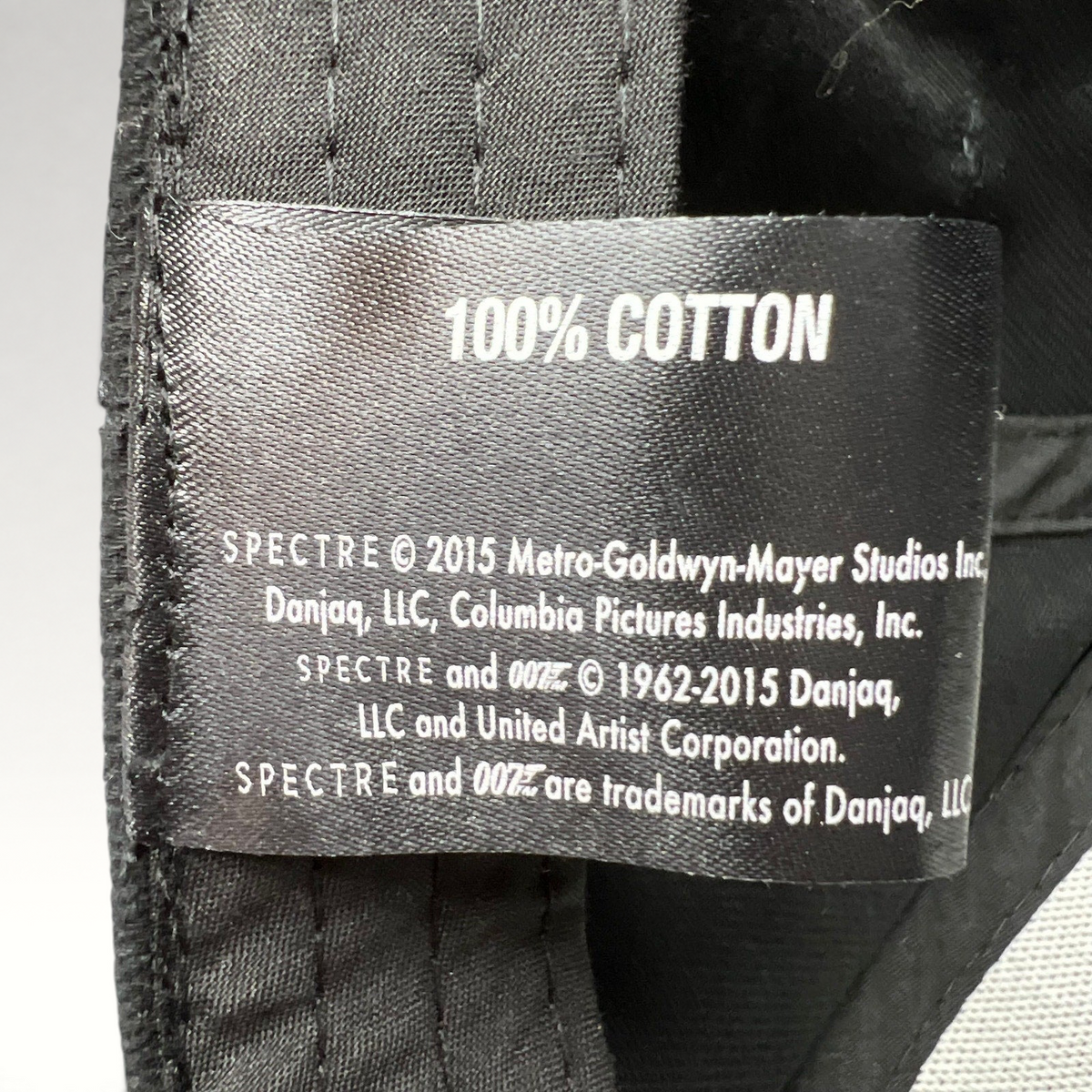 Raree Finds 2015 Spectre 007 promotional hat interior tag showing 100% cotton and official MGM Danjaq licensing info
