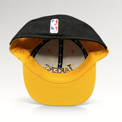 Raree Finds vintage Reebok Los Angeles Lakers fitted hat featuring a black crown, gold brim, and purple embroidery.