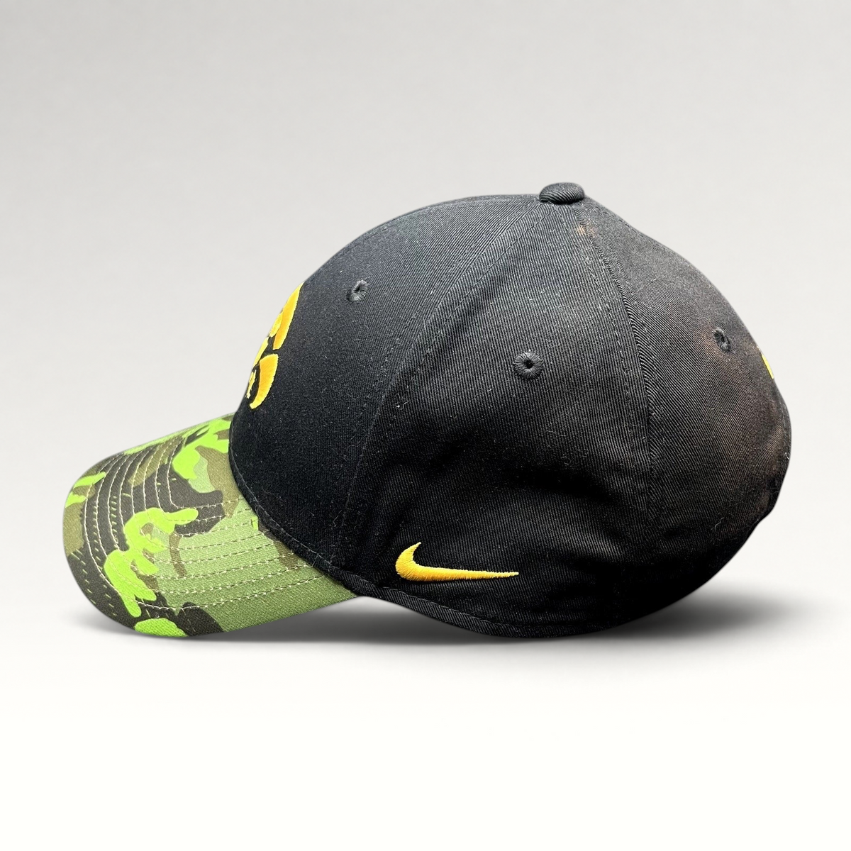 Raree Finds Nike Iowa Hawkeyes Legacy91 strapback hat with a black crown, green camo visor, and gold embroidered logo.