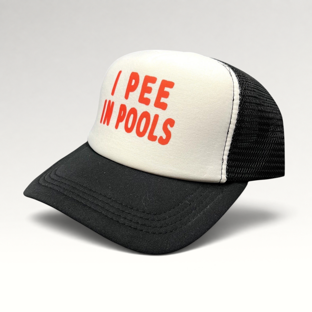 Raree Finds novelty trucker hat with white foam front, red I PEE IN POOLS text, black mesh back, and black brim.