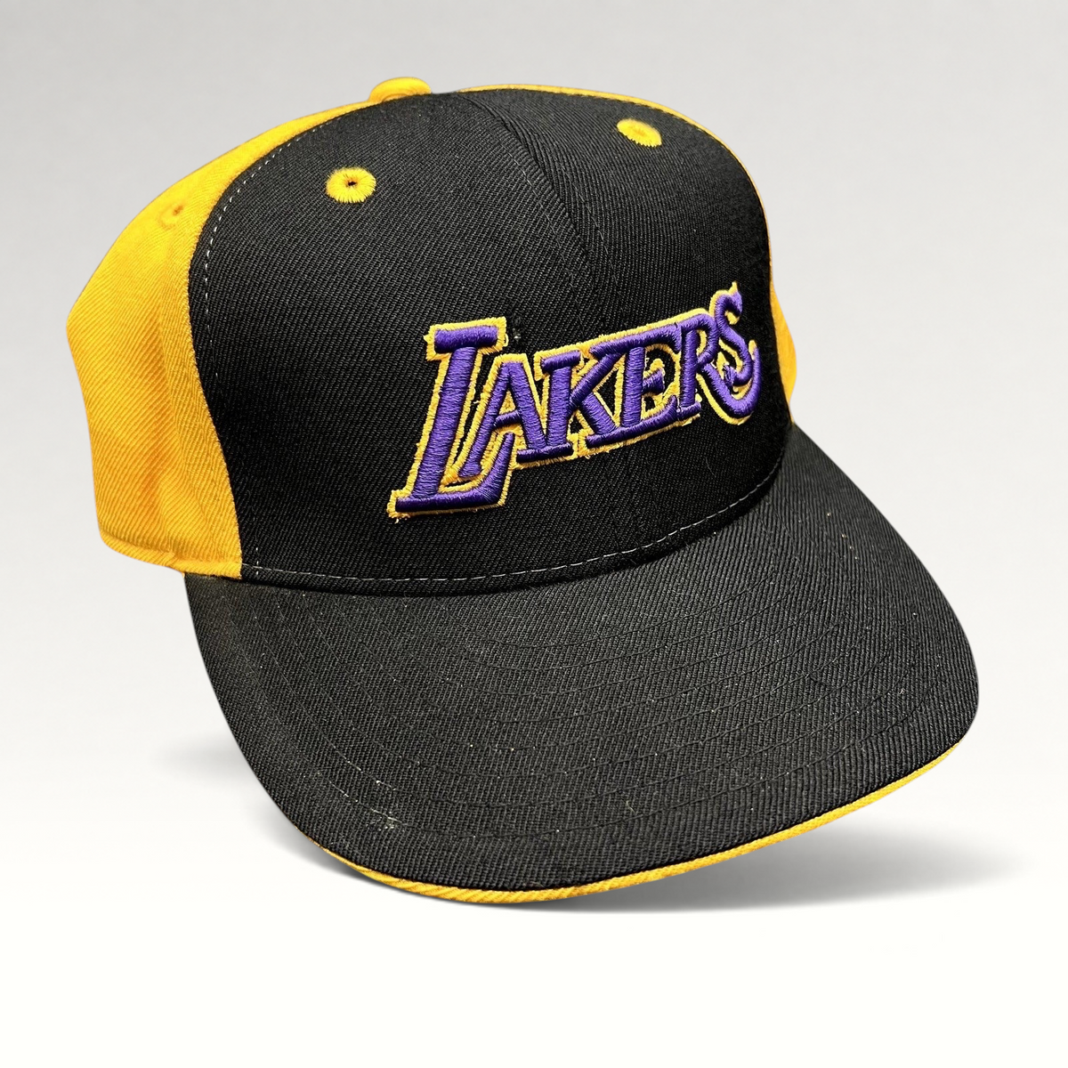 Raree Finds vintage Reebok Los Angeles Lakers fitted hat featuring a black crown, gold panels, and purple embroidery.