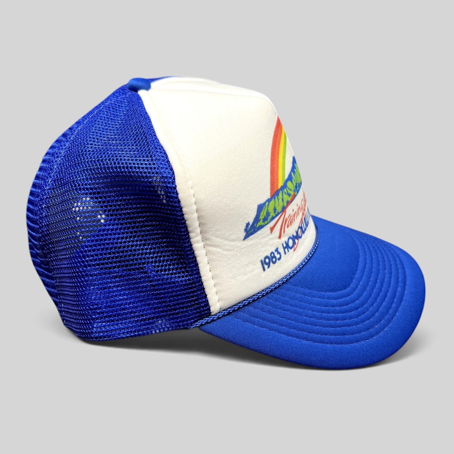 Raree Finds vintage 1983 Honolulu Marathon trucker hat with white foam front, blue mesh back, and rainbow graphic.