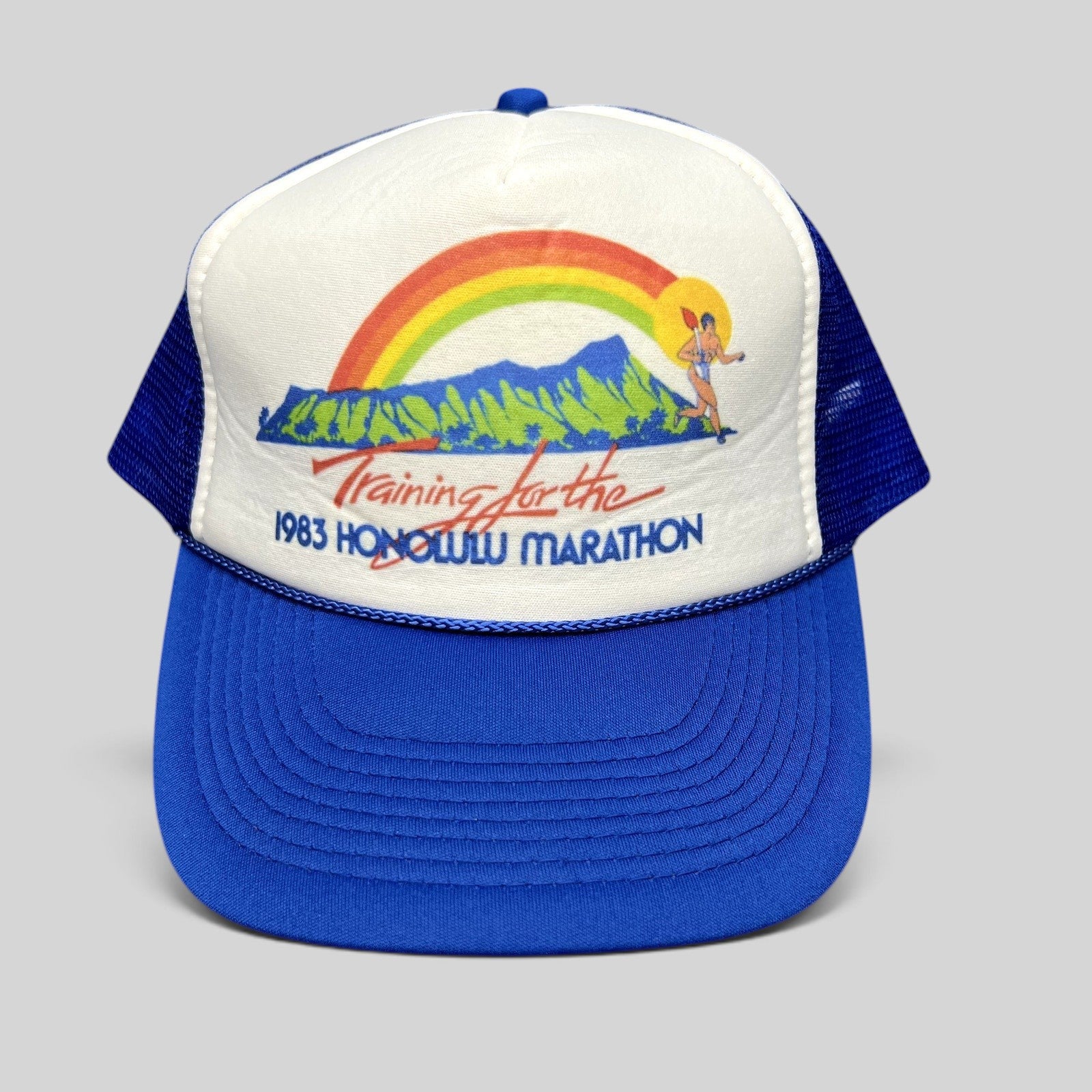 Raree Finds vintage 1983 Honolulu Marathon trucker hat with white foam front, blue mesh back, and rainbow graphic.