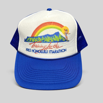 Raree Finds vintage 1983 Honolulu Marathon trucker hat with white foam front, blue mesh back, and rainbow graphic.
