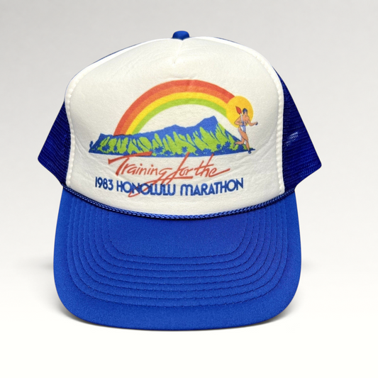 Raree Finds vintage 1983 Honolulu Marathon trucker hat with white foam front, blue mesh back, and rainbow graphic.