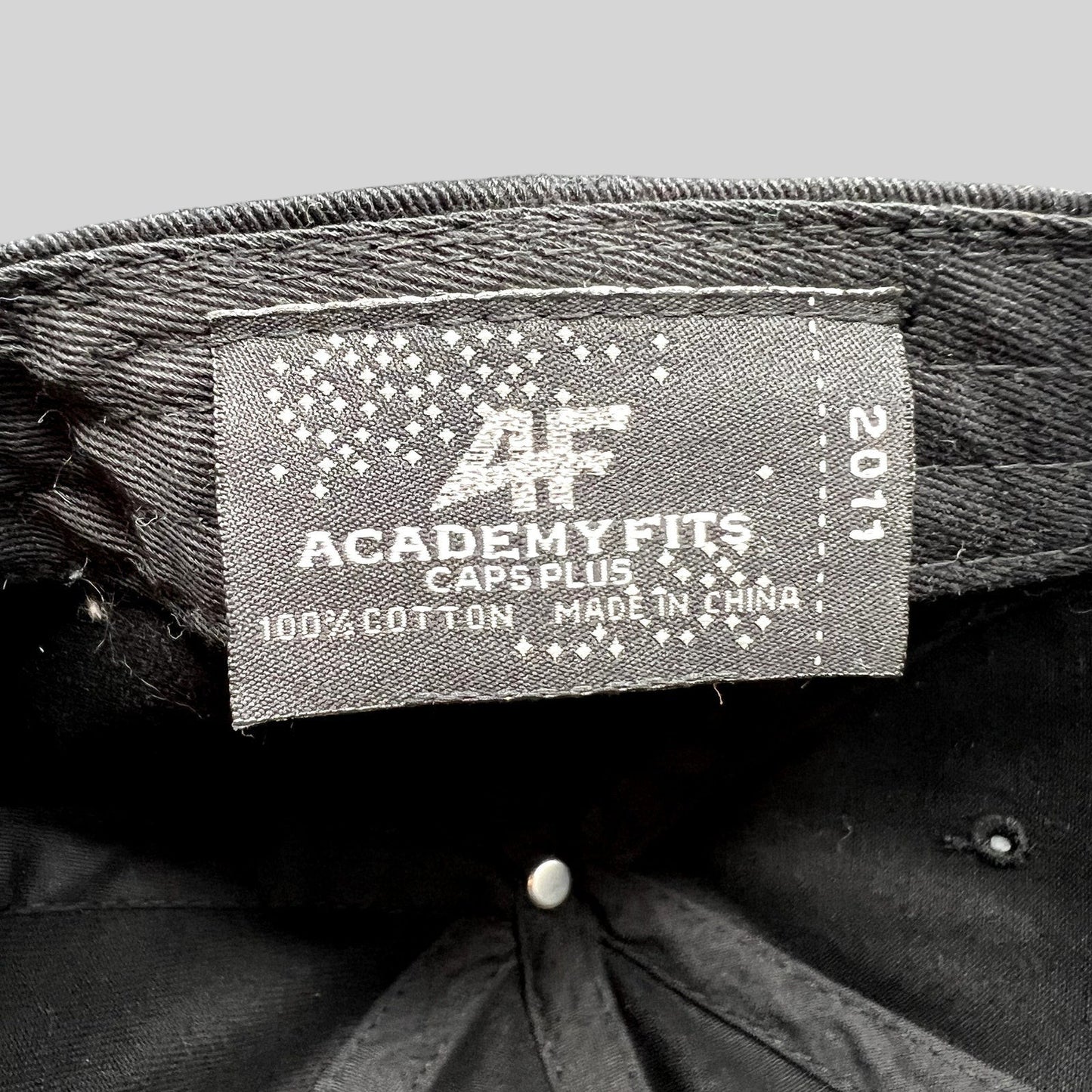 Raree Finds black cotton dad cap interior label showing AcademyFits Caps Plus branding and 2011 production year