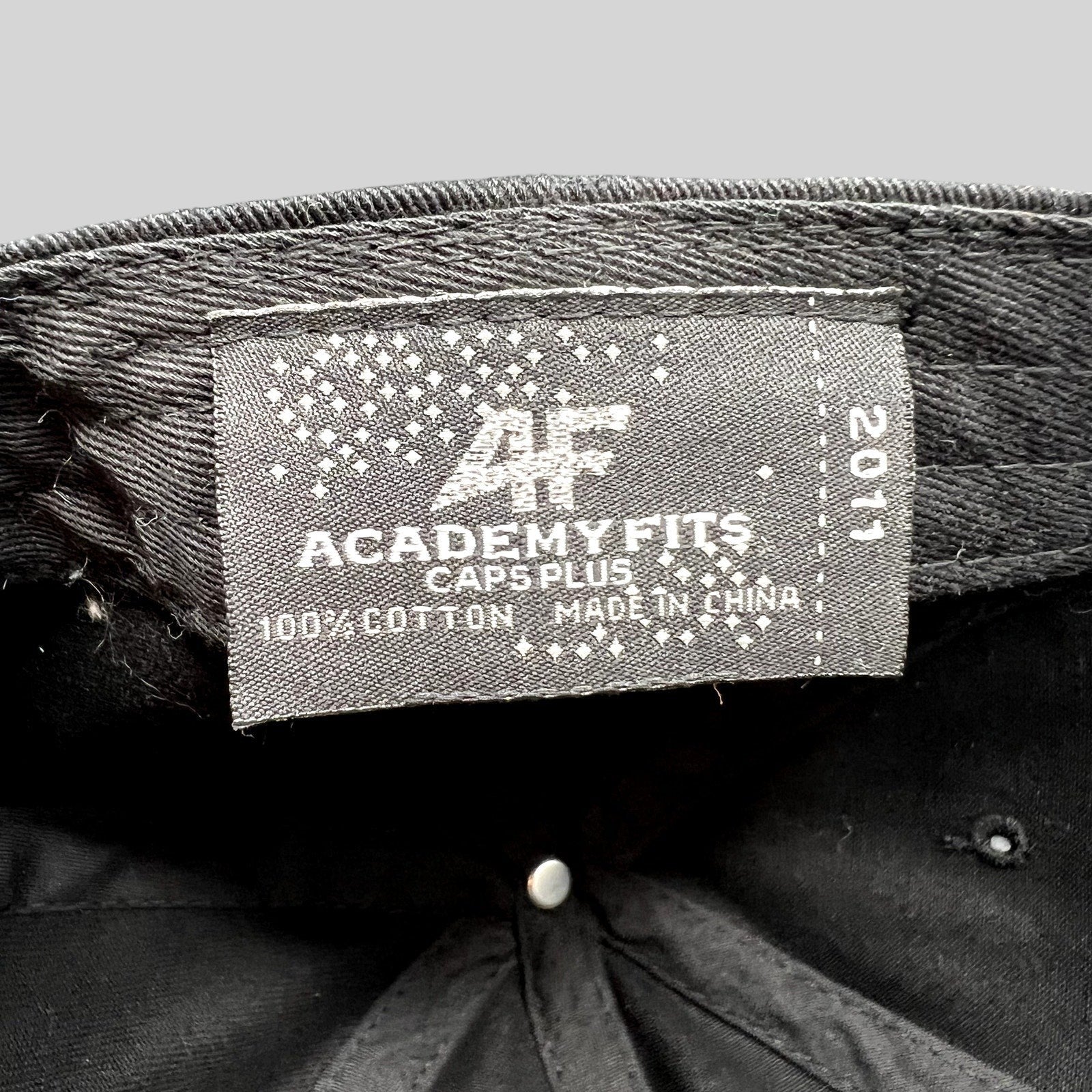 Raree Finds black cotton dad cap interior label showing AcademyFits Caps Plus branding and 2011 production year