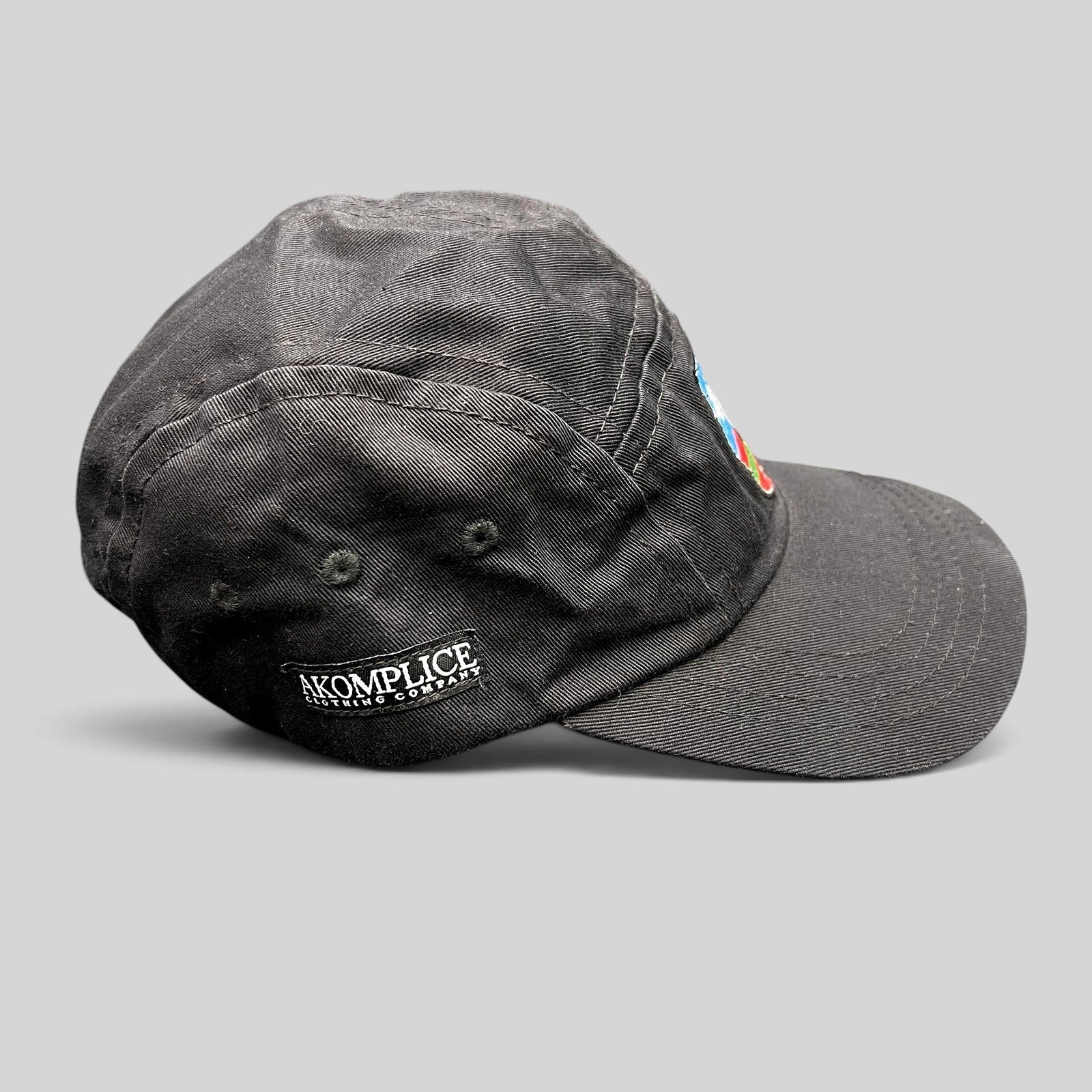 Raree Finds black Akomplice Clothing strapback hat with side logo embroidery and a front multicolor crest patch