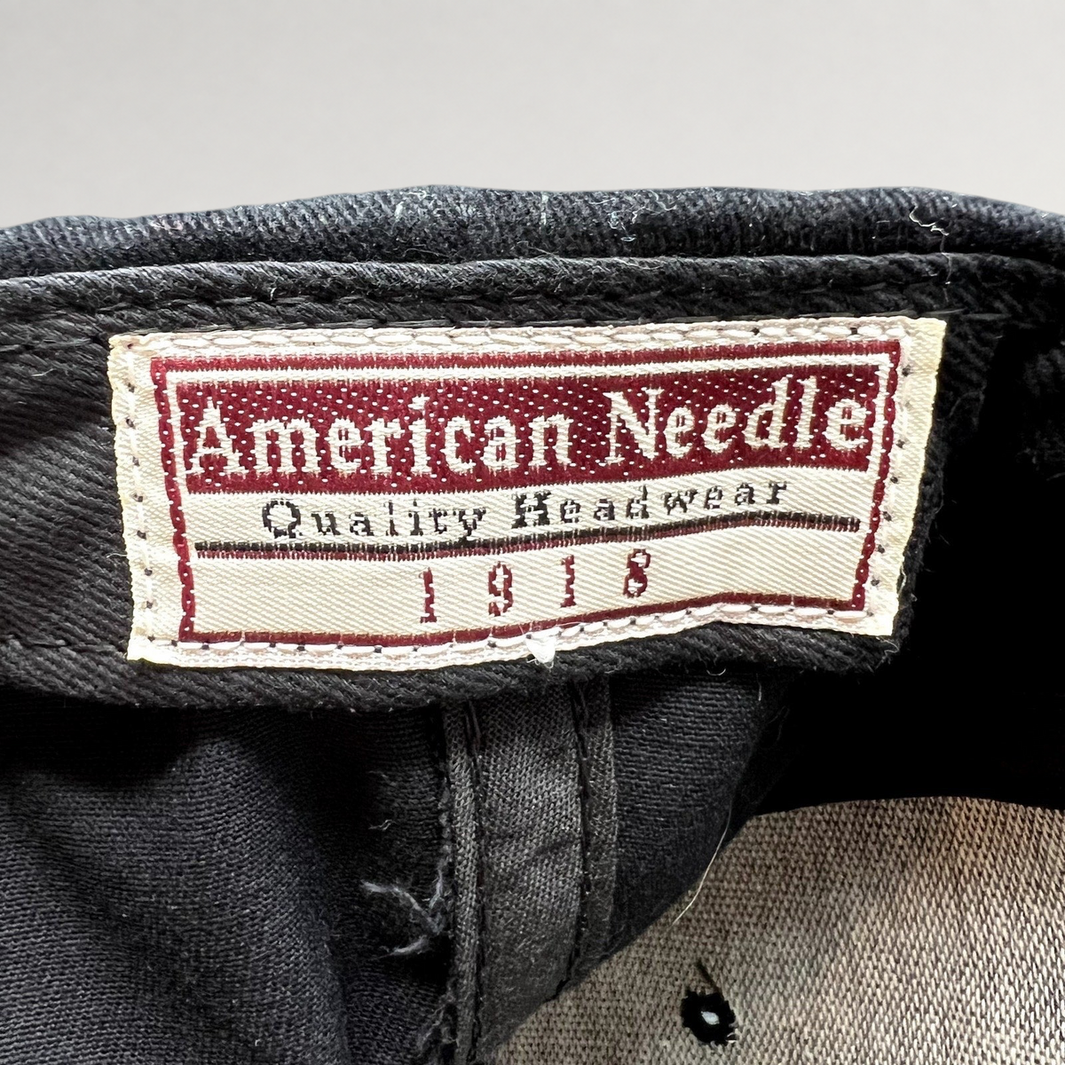 Raree Finds vintage American Needle hat interior tag with red and white branding on black cotton twill fabric