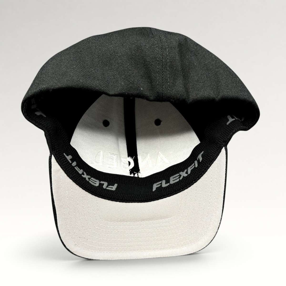 Raree Finds black Angel Studios Flexfit cap with white interior lining and branded sweatband, viewed from underneath.